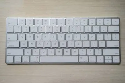 Teclado de um iMac, com as teclas mais baixas. Sua estrutura é prata e as teclas brancas.