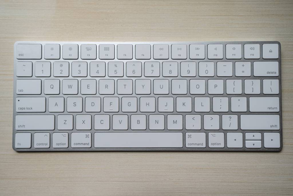 Teclado de um iMac, com as teclas mais baixas. Sua estrutura é prata e as teclas brancas. 