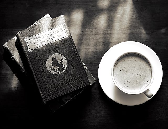 Livro de poemas em cima da mesa e um xícara de café.